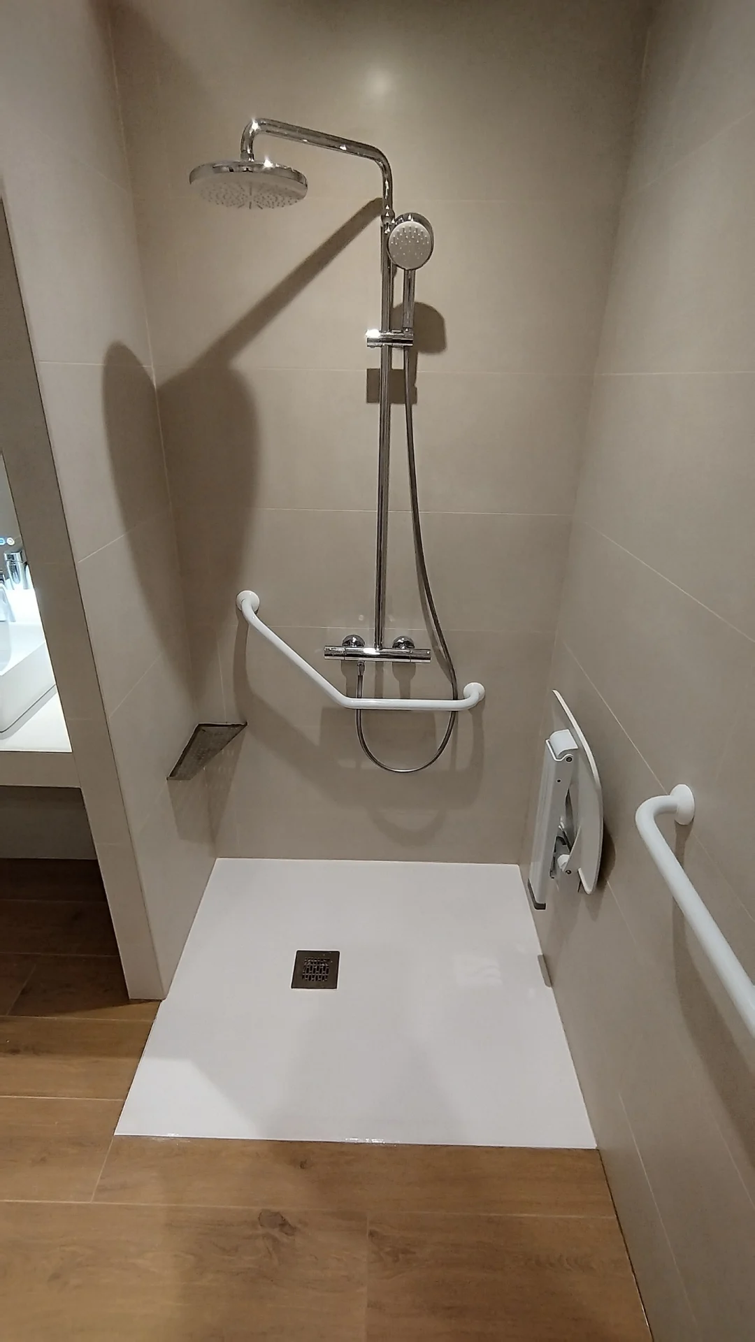 La douche PMR, accessible sans marche. Rénovation appartement PMR Montpellier : douche sur receveur affleurant, barres de maintien et siège rabattable