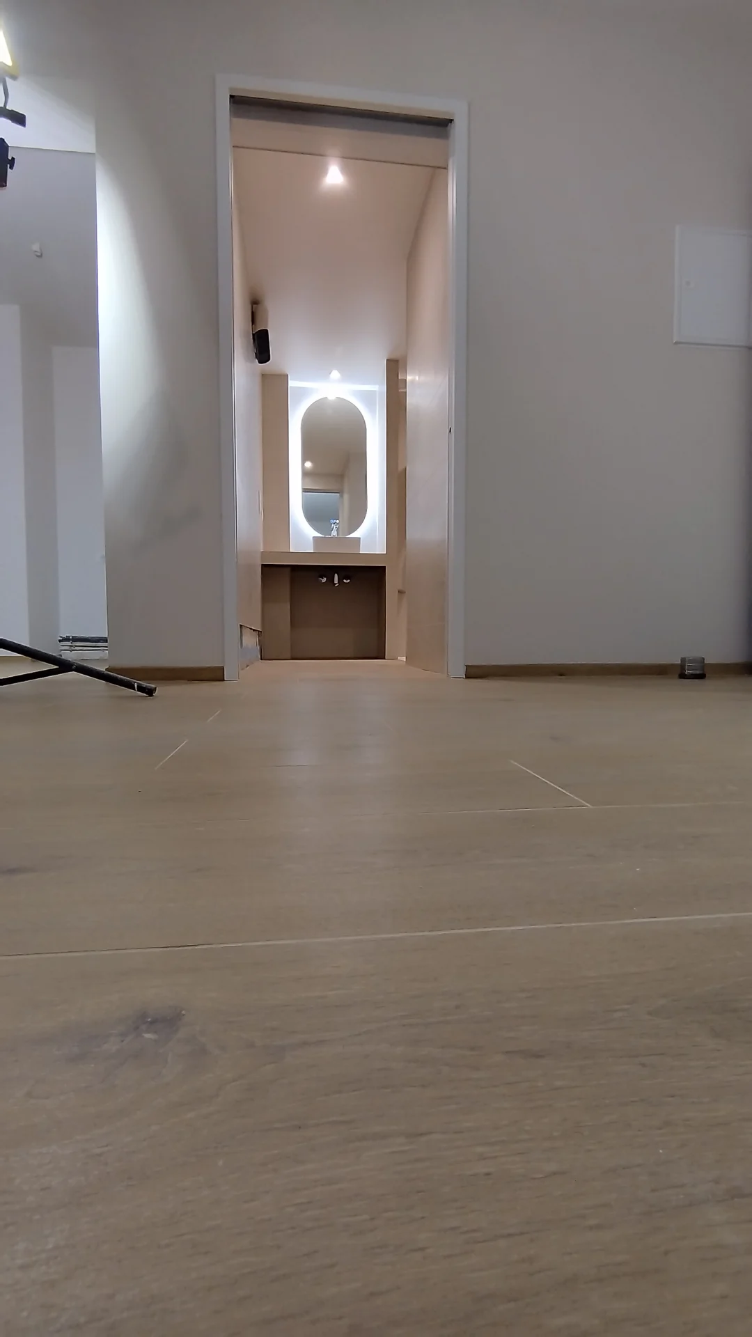 Une circulation dégagée d'une pièce à l'autre. Vue du séjour vers la salle de bain PMR éclairée, sol en carrelage effet bois, appartement Boutonnet