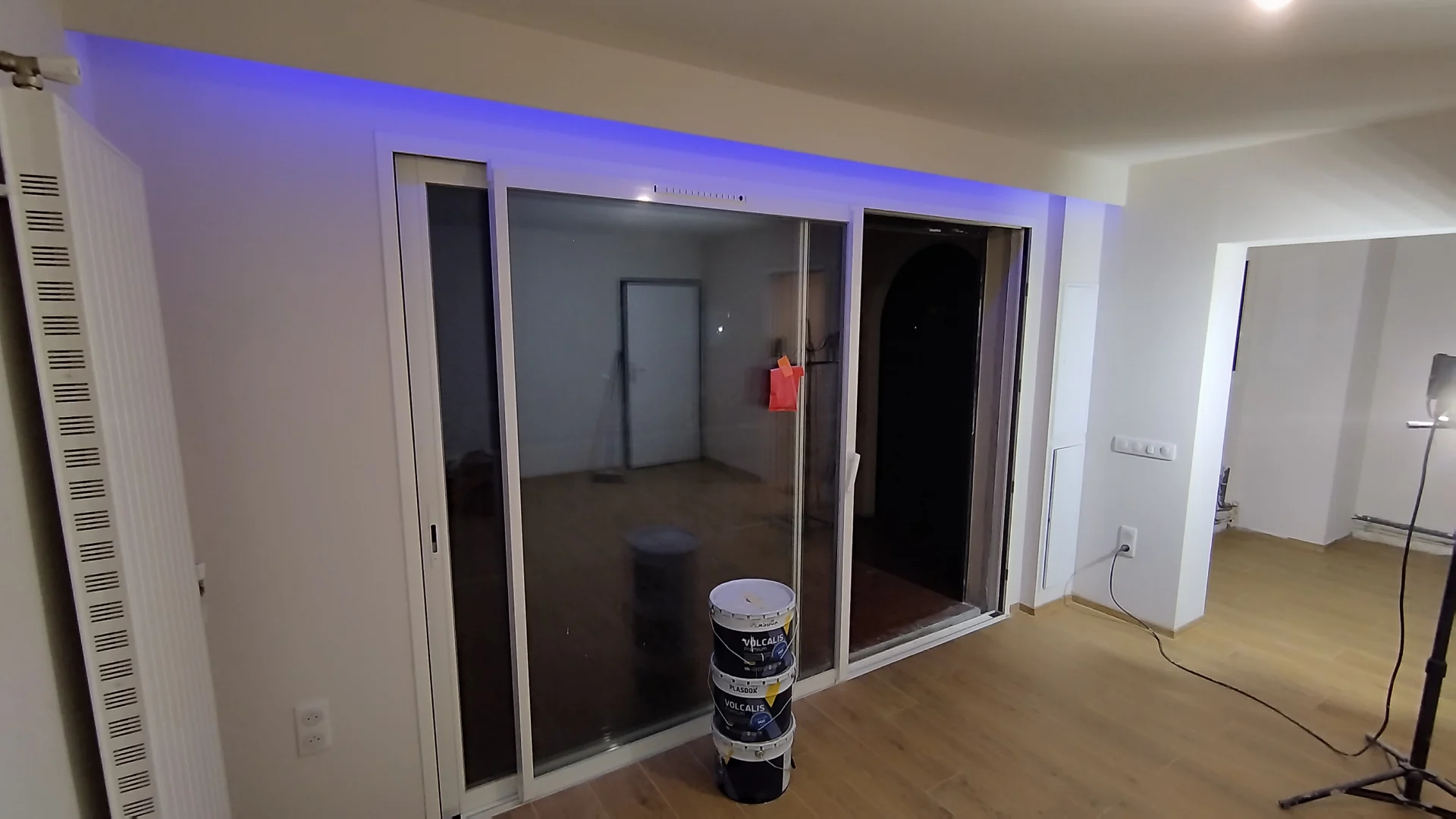 Le séjour après peinture et pose du sol. Séjour repeint en blanc avec baie vitrée, bandeau lumineux et carrelage effet bois à Montpellier