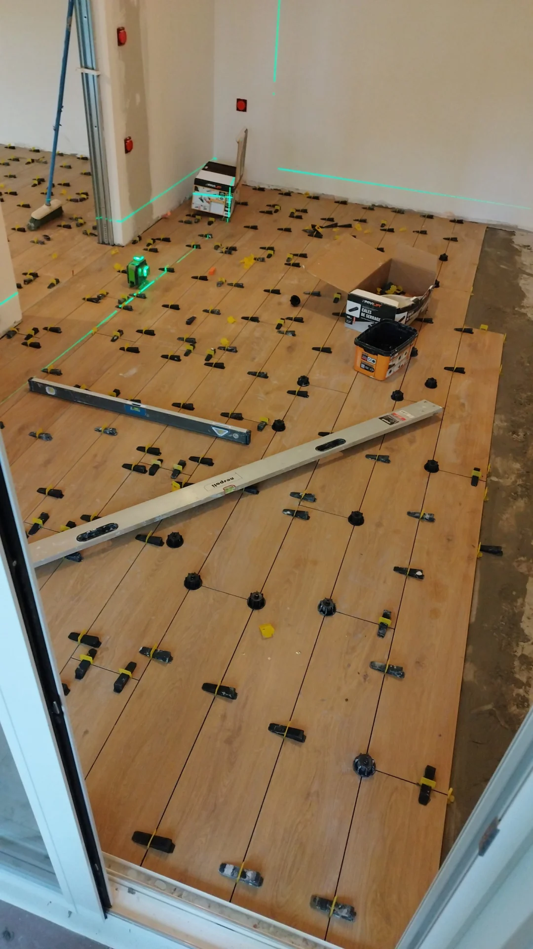 Une pose au laser pour un sol bien plan. Pose de carrelage grand format effet bois avec niveau laser et système de calage à Montpellier