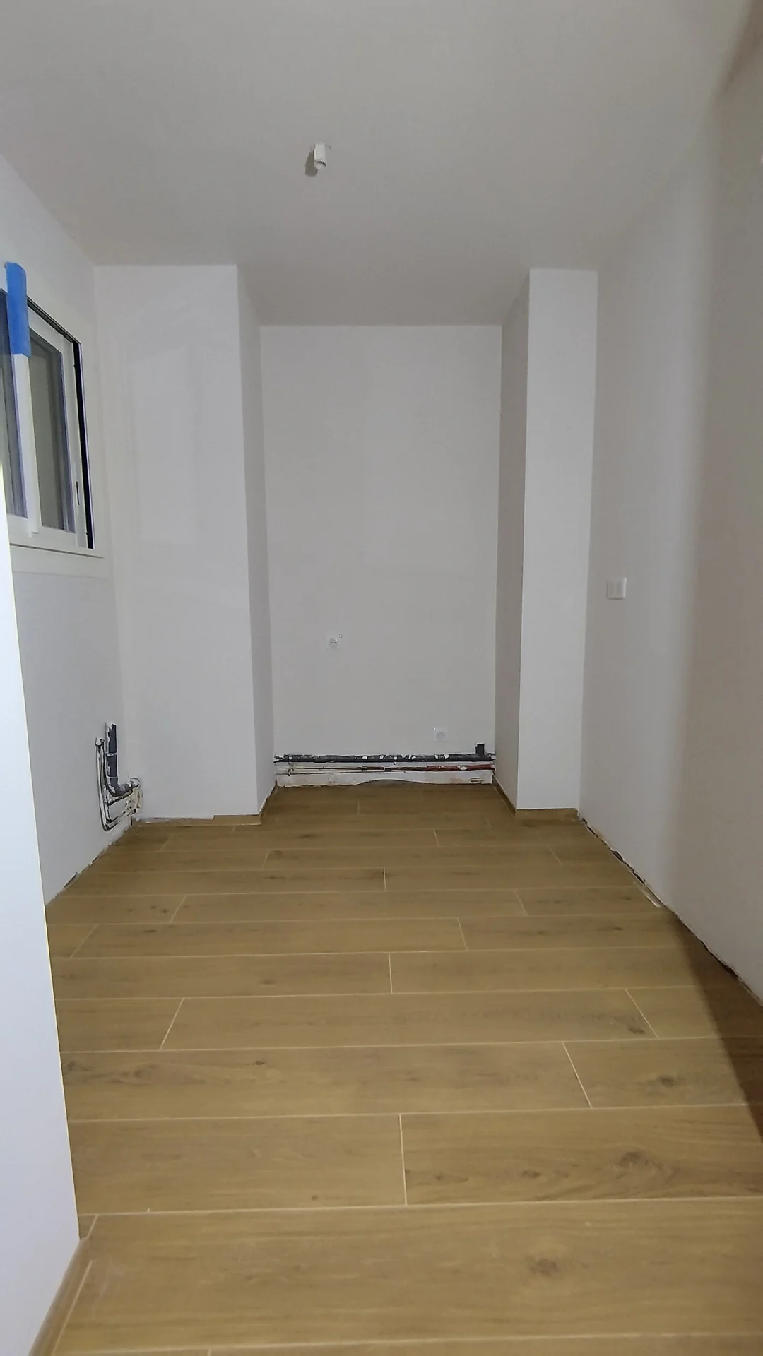 Les nouvelles cloisons, prêtes pour les équipements. Pièce après plâtrerie et enduits, arrivées d'eau en attente et sol effet bois, rénovation PMR Montpellier